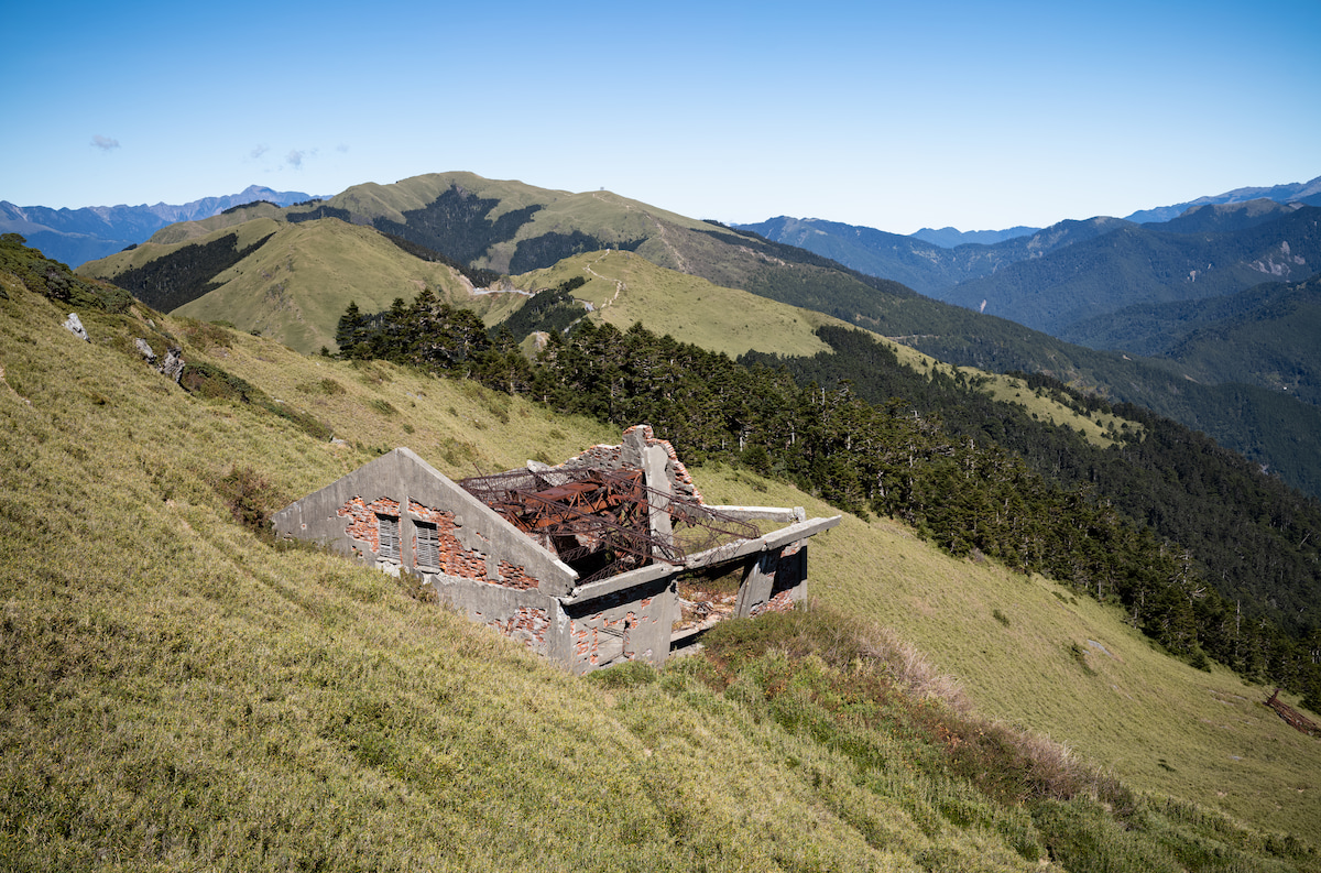 合歡東峰最具代表性的地標：廢棄滑雪纜車站遺跡，於一九九○年前後廢棄。背景的草原山頭最高處為合歡北峰，其左手邊遠方背景最高的頂峰，就是臺灣第二高峰：雪山主峰！